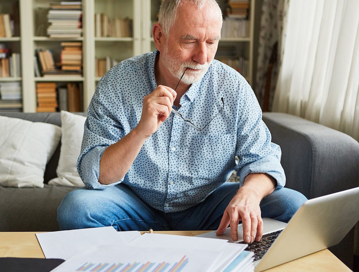 Homme âgé assis devant un ordinateur portable