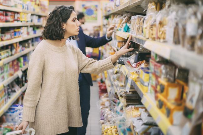 Uma mulher está olhando para uma prateleira de um supermercado.