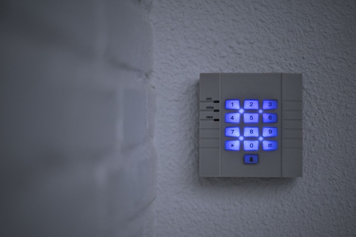 Alarme de sécurité à clavier rétroéclairée en bleu fixée au mur d'un couloir sombre