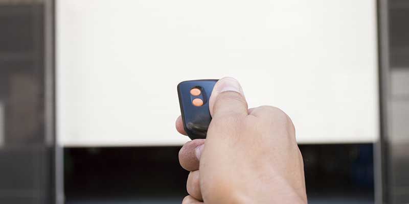 Main tenant un smartphone noir à écran bleu, pointée vers une porte lumineuse