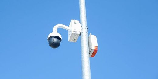 Caméra de sécurité fixée sur un poteau sur fond de ciel bleu clair