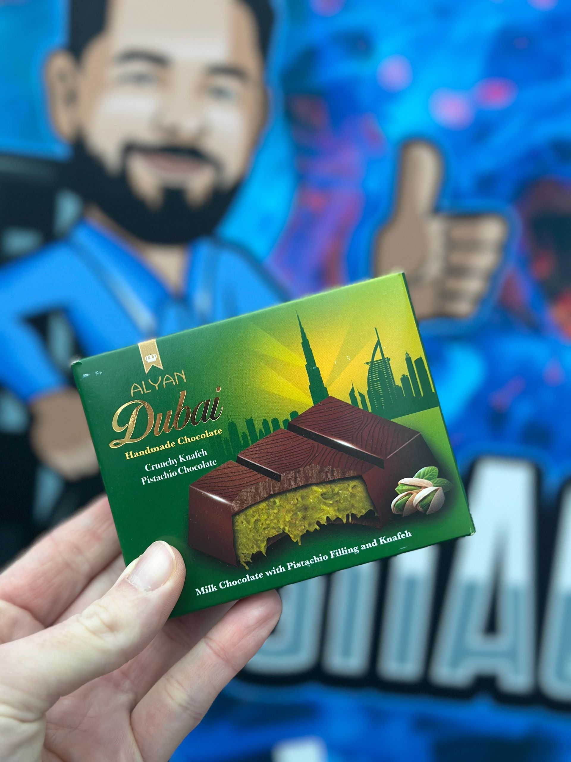 Eine Person hält einem Mann ein Stück Schokolade vor die Nase und zeigt ihm den Daumen nach oben