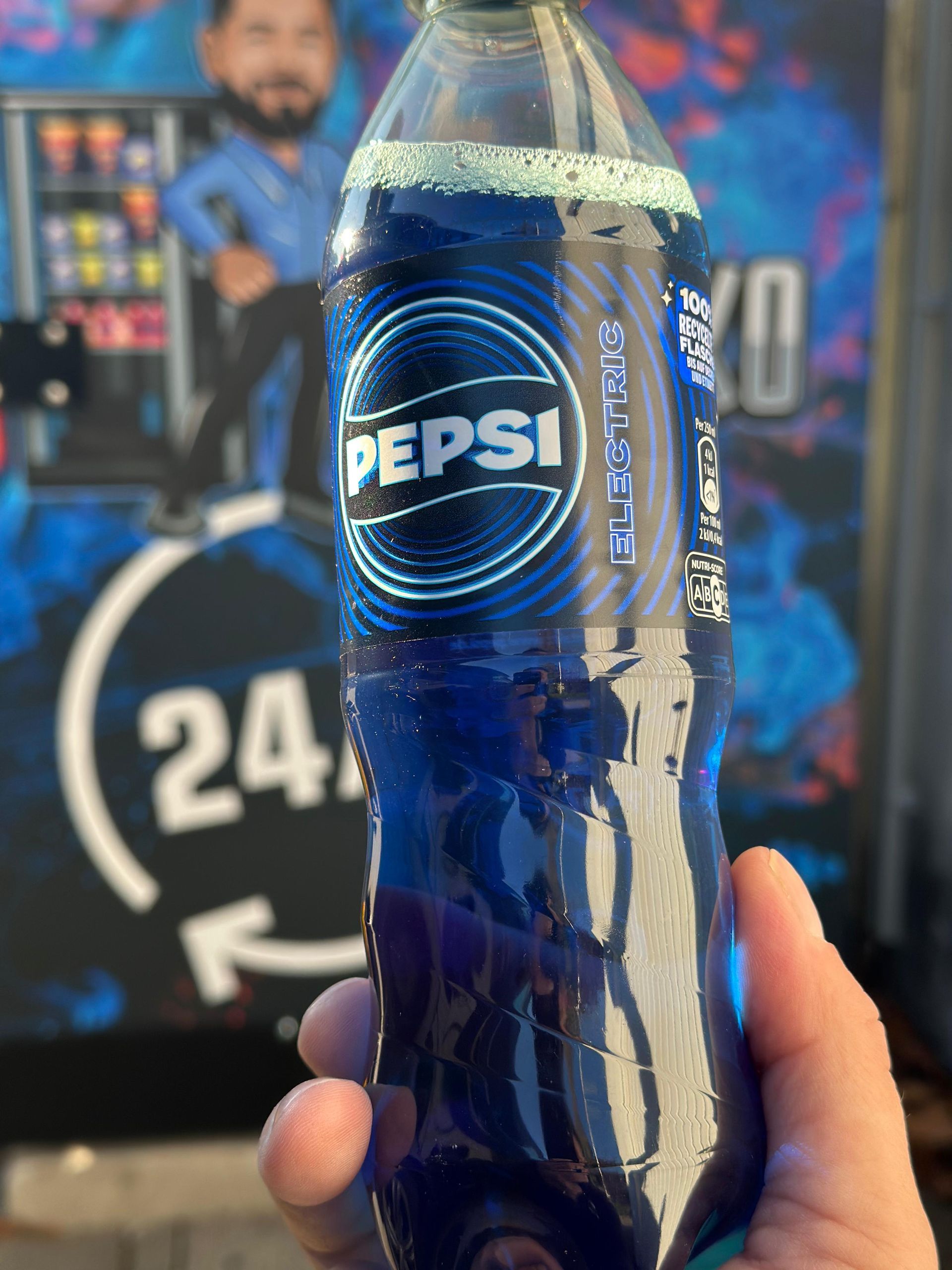 Eine Person hält eine blaue Pepsi-Flasche in der Hand.