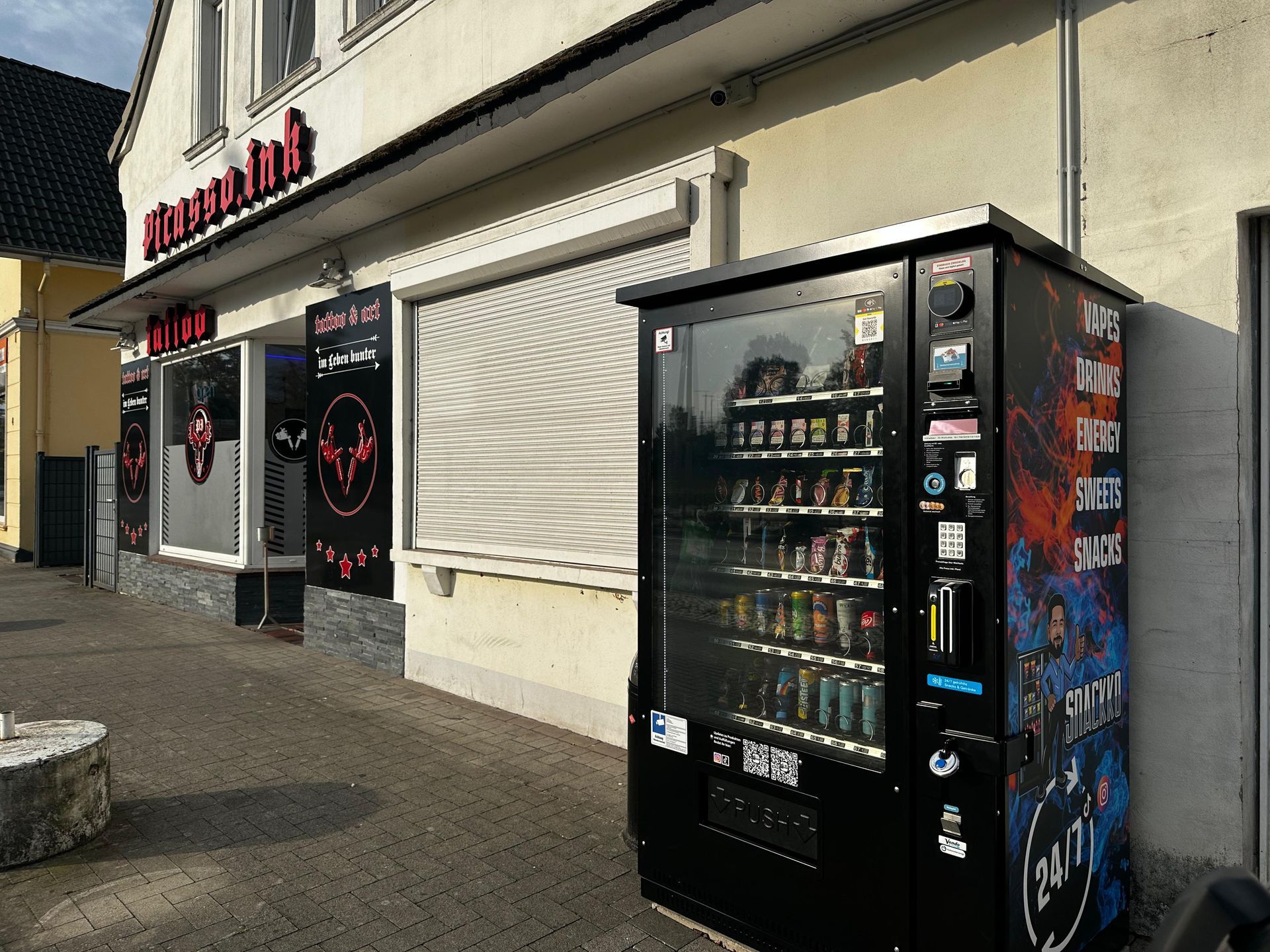 Vor einem Gebäude steht ein Verkaufsautomat.
