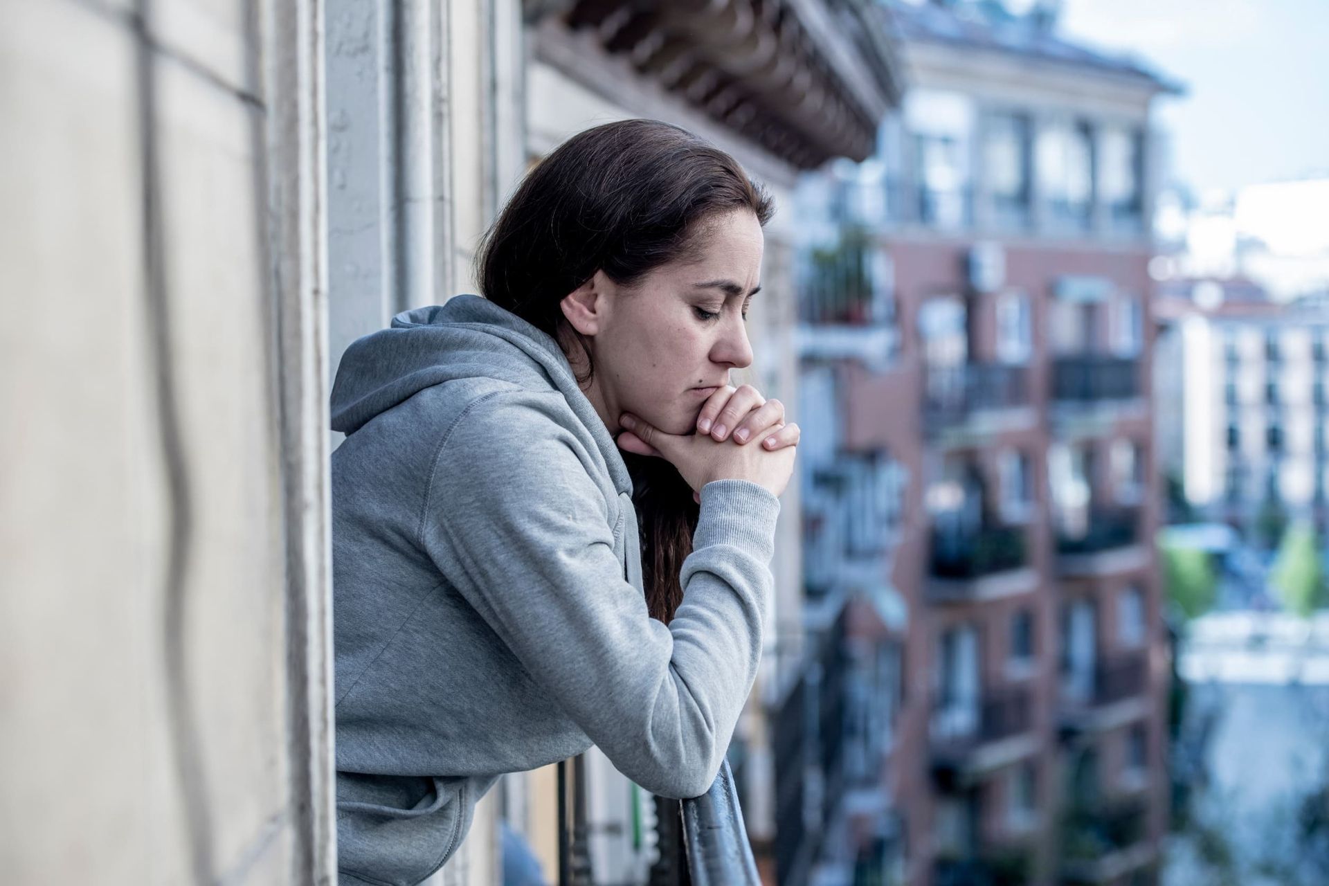 Una mujer está parada en un balcón mirando por la ventana.