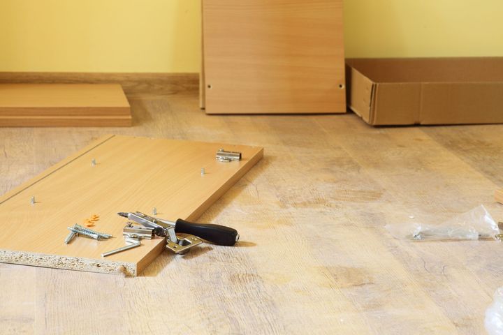 Montaje de muebles: paneles de madera y herramientas esparcidas sobre un suelo de color claro.