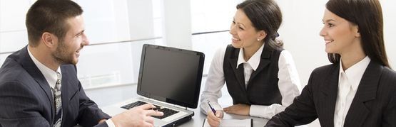 Un hombre y dos mujeres están reunidos frente a una computadora portátil.