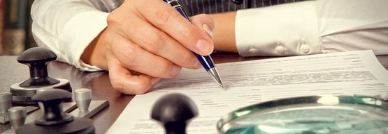 Una persona está escribiendo en un trozo de papel con un bolígrafo.