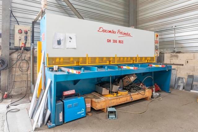 Grande cisaille métallique bleue et blanche dans un atelier.