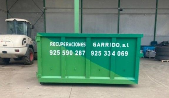 Un contenedor de basura industrial verde con información de contacto
