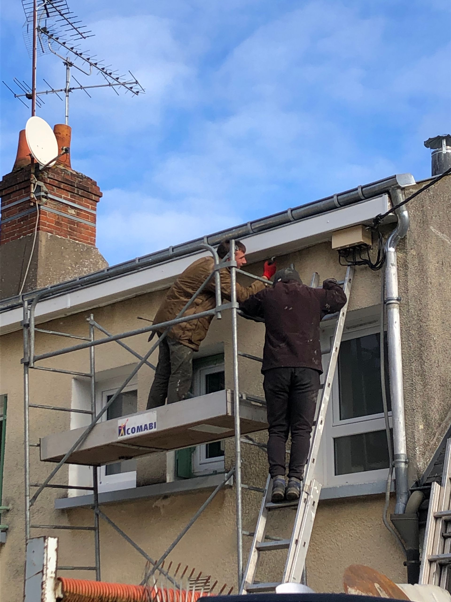 Deux couvreurs nettoient une façade