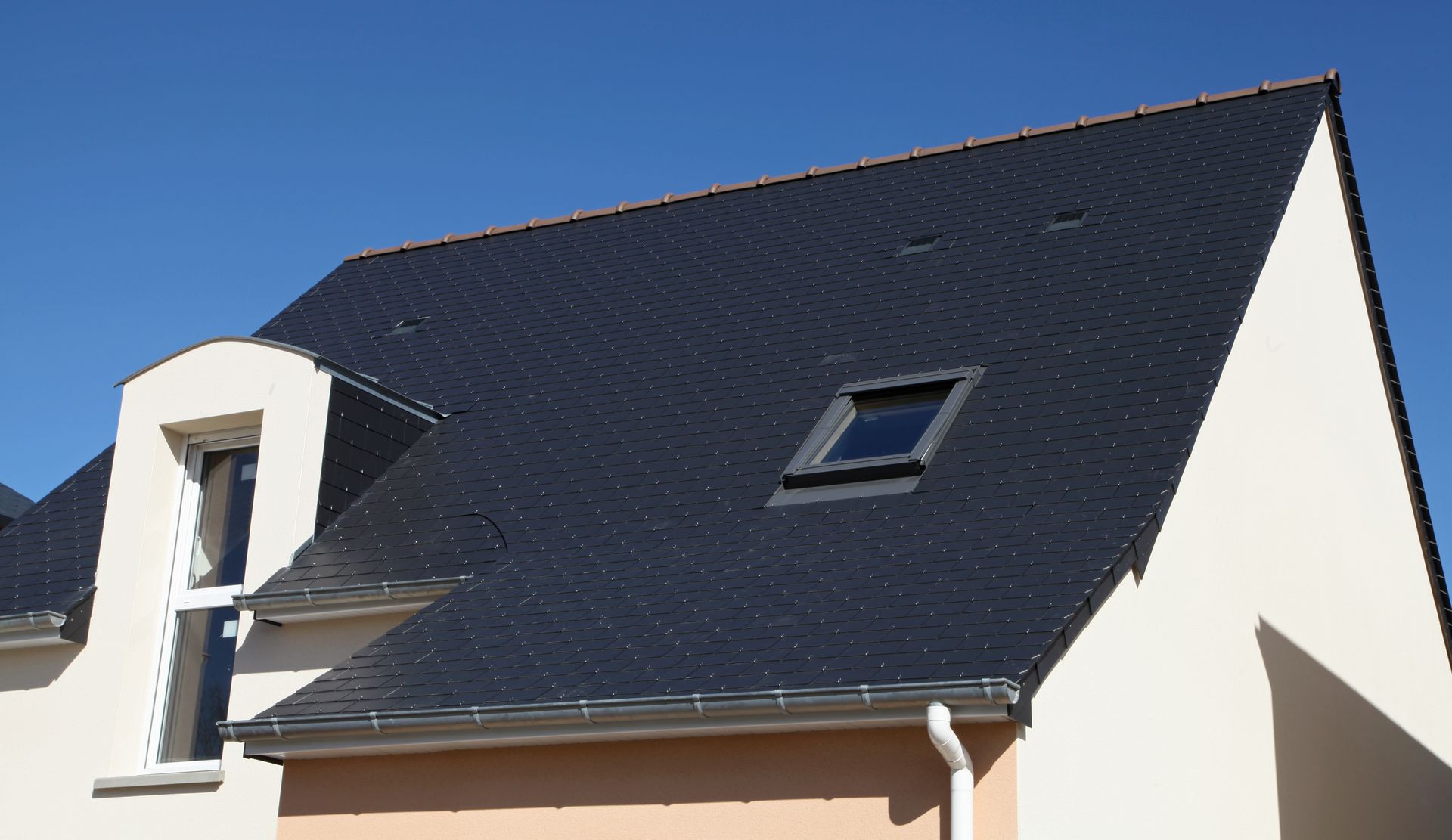 Une toiture pentue d'ardoises et des gouttières