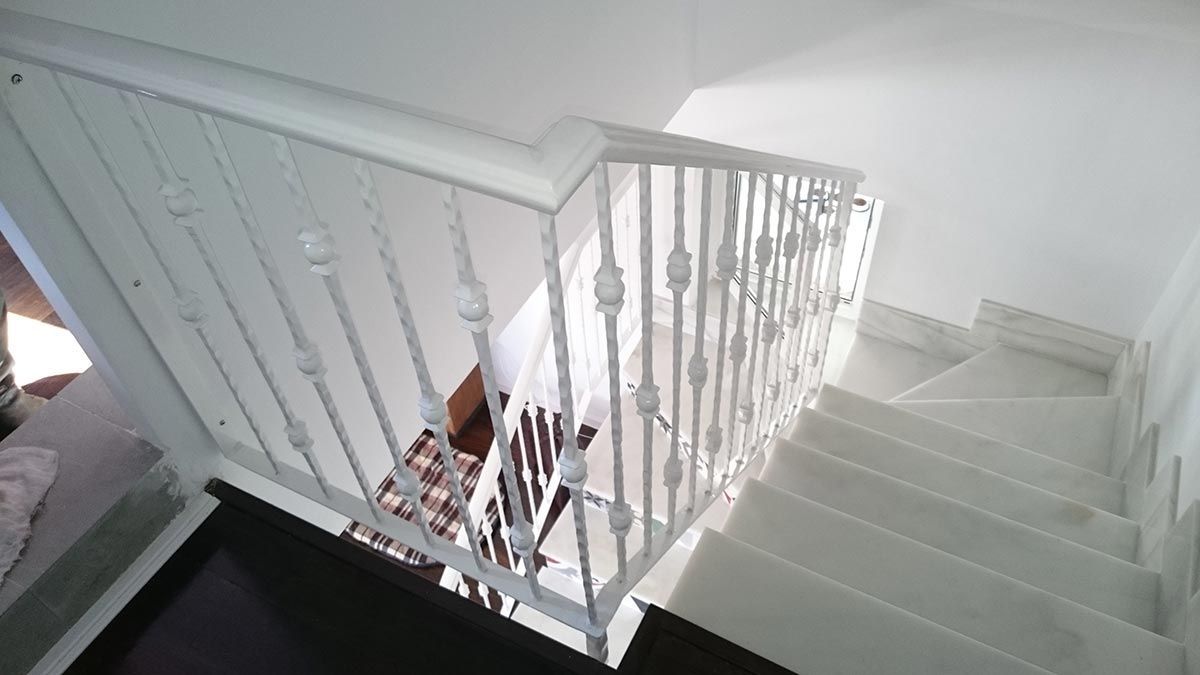 Escalera blanca con barandillas decorativas y pasamanos.