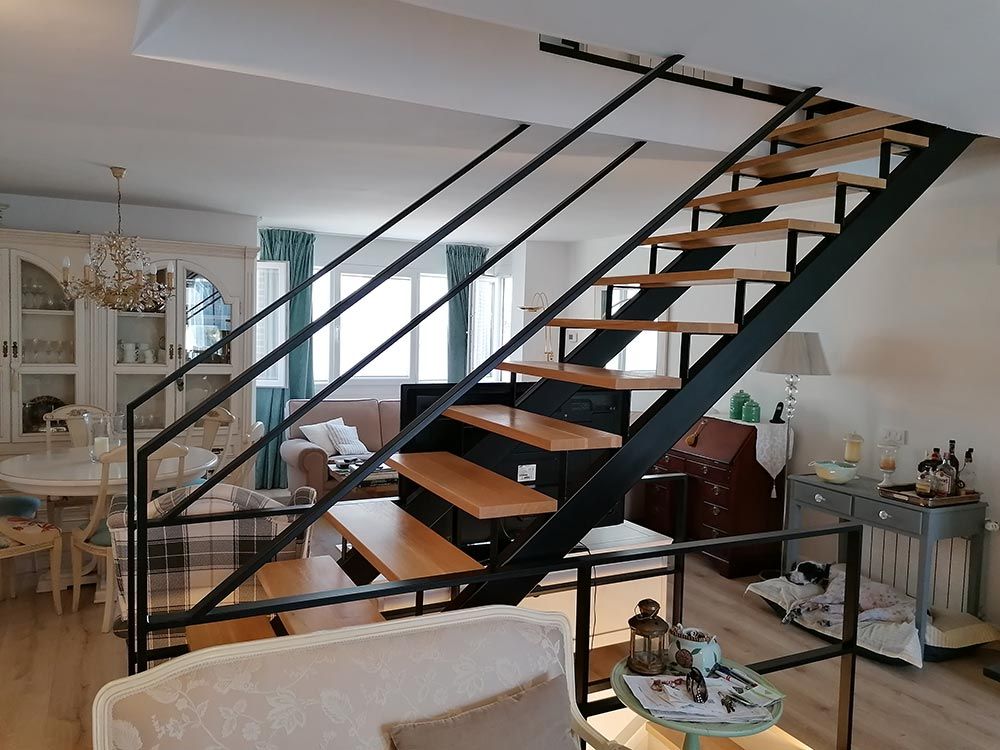 Una escalera de metal y madera conduce a un nivel superior en una sala de estar moderna y luminosa.