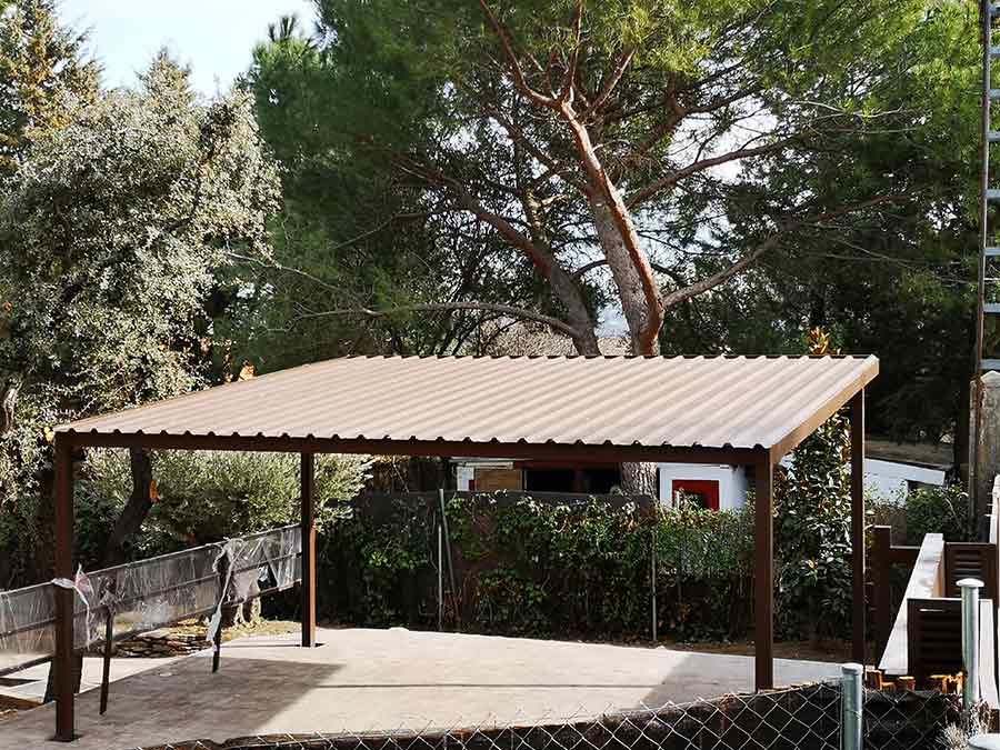 Cochera de metal marrón en un patio trasero con árboles y una cerca.