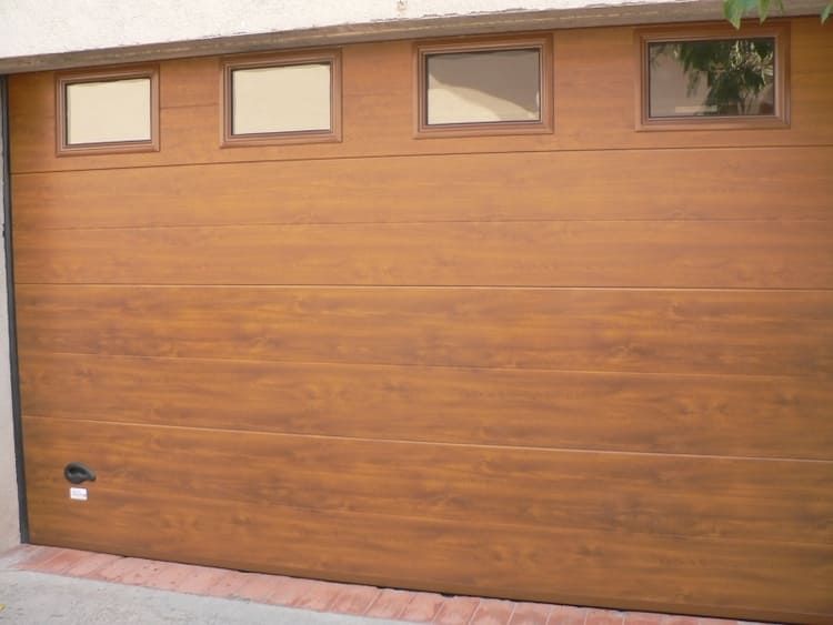 Puerta de garaje marrón con cuatro pequeñas ventanas en la parte superior.