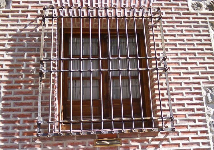 Ventana con rejas de seguridad metálicas en un edificio de ladrillo.
