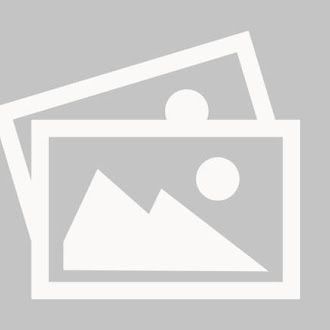 Une BMW break blanche garée sur un parking goudronné, avec un arbre, une maison et des montagnes en arrière-plan.