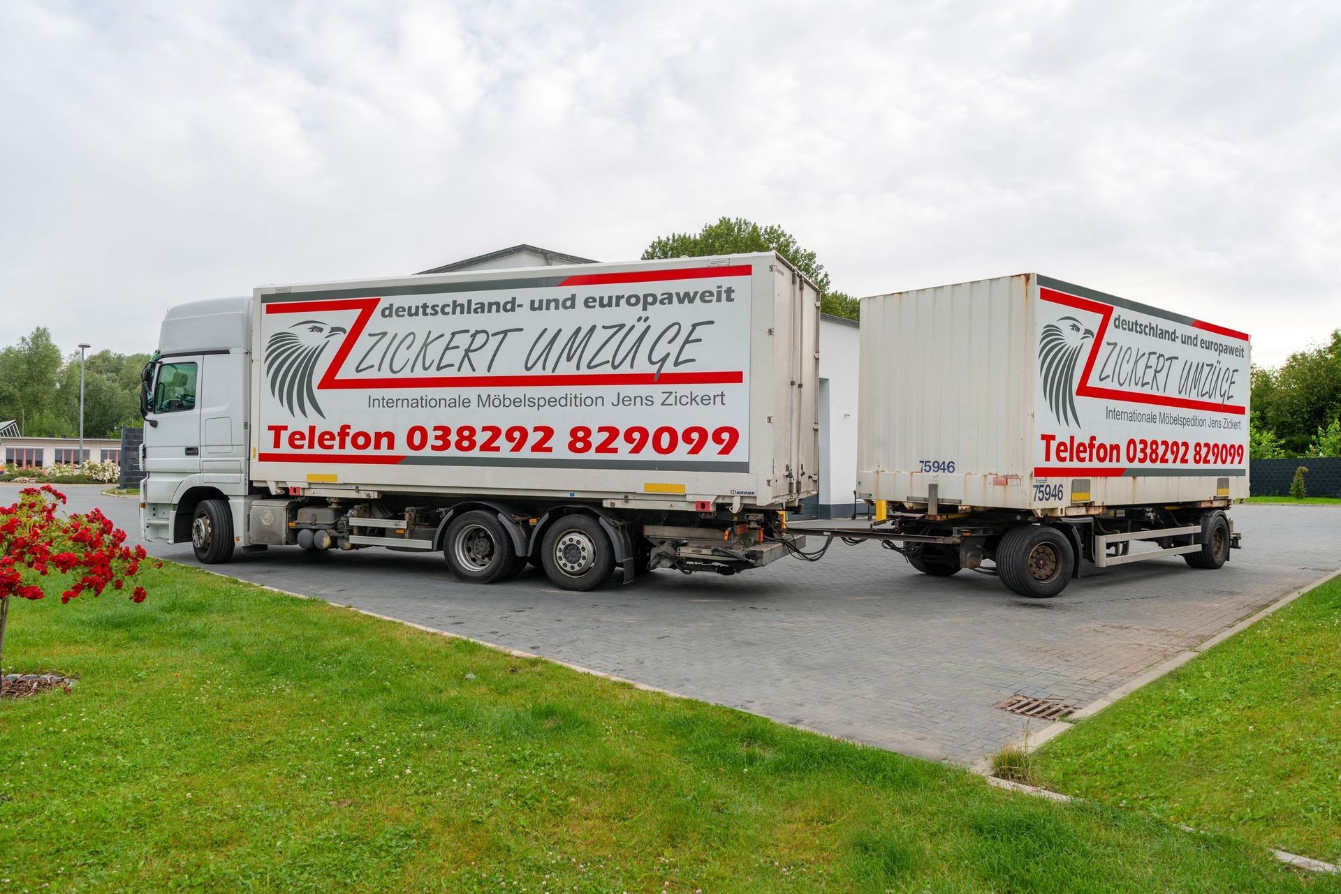 Weißer Umzugswagen und Anhänger von ZICKERT UMZÜGE auf Schotter geparkt, mit grünem Gras.