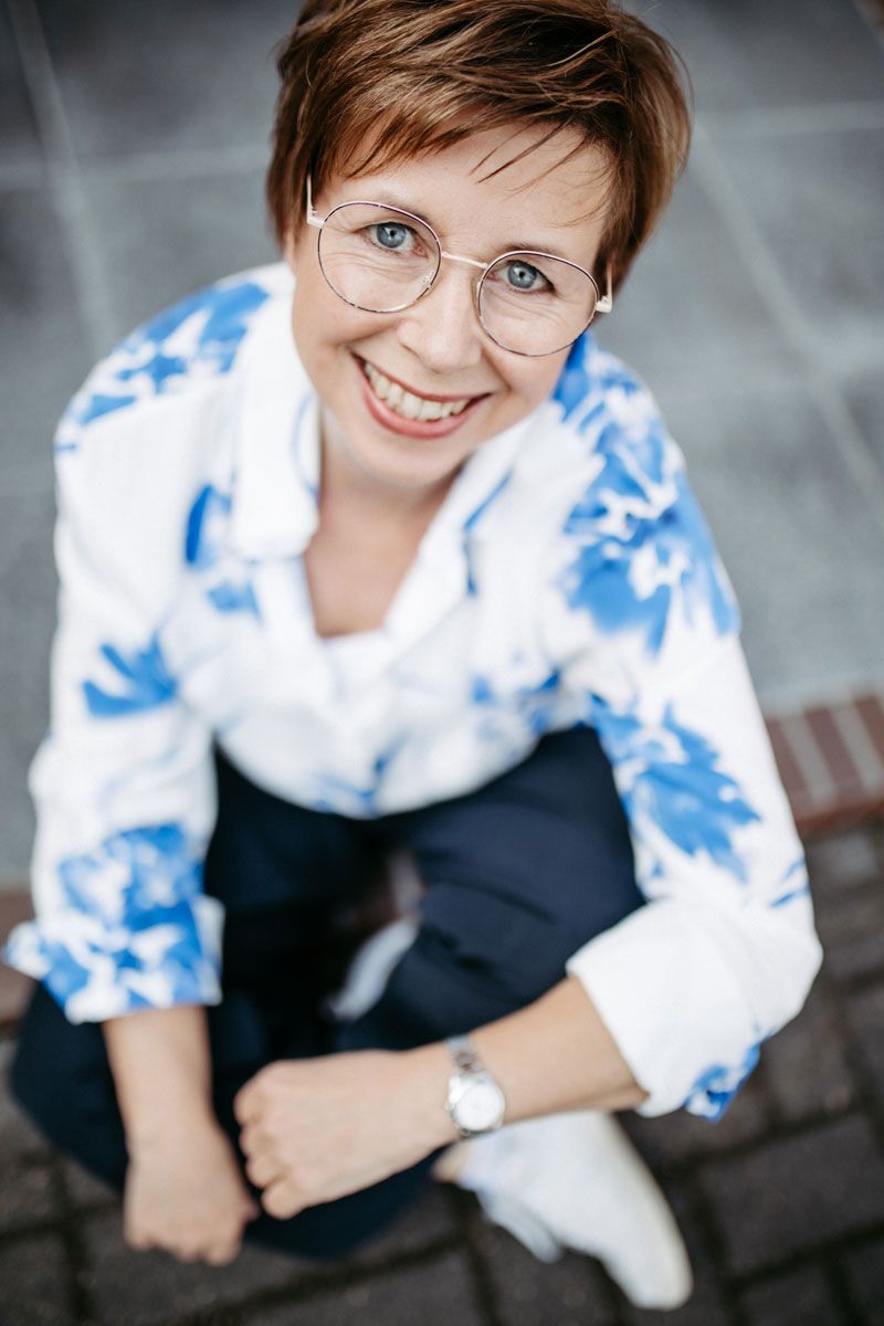 Eine Frau lächelt, während sie auf einem Stuhl vor einem Spiegel sitzt