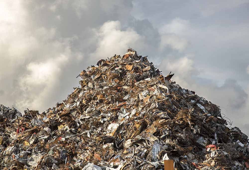 Gran montón de basura y chatarra bajo un cielo nublado.