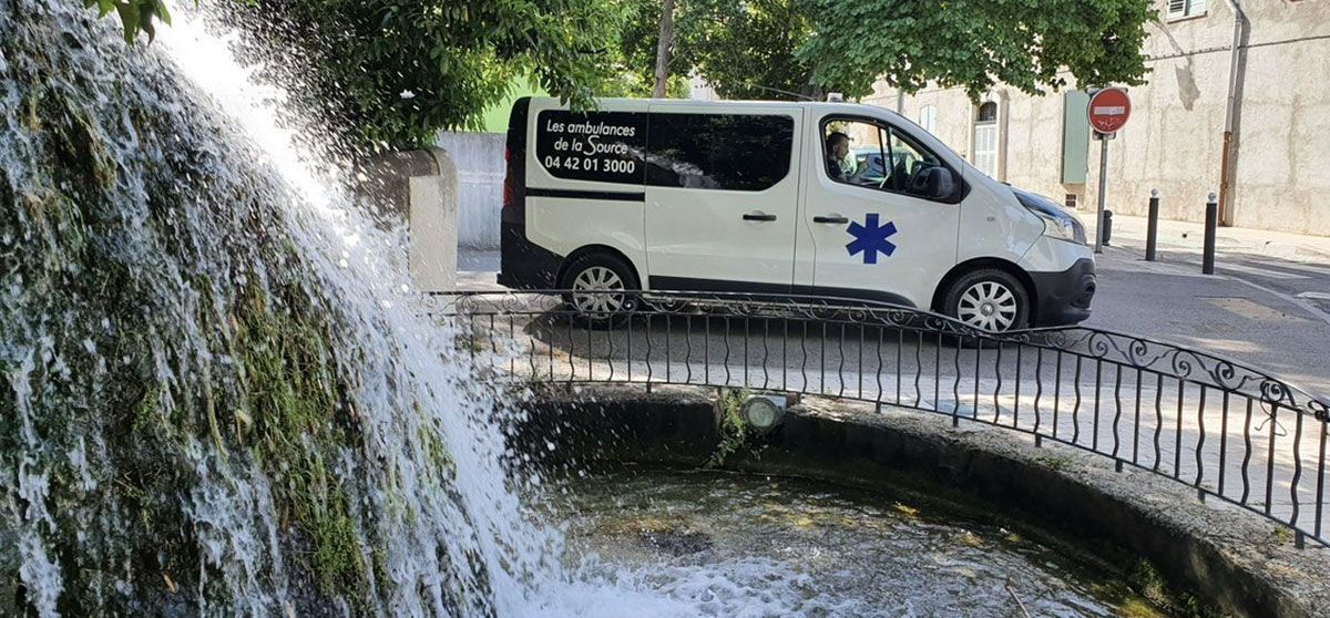 Ambulance arrêtée à un carrefour avec une fontaine à côté