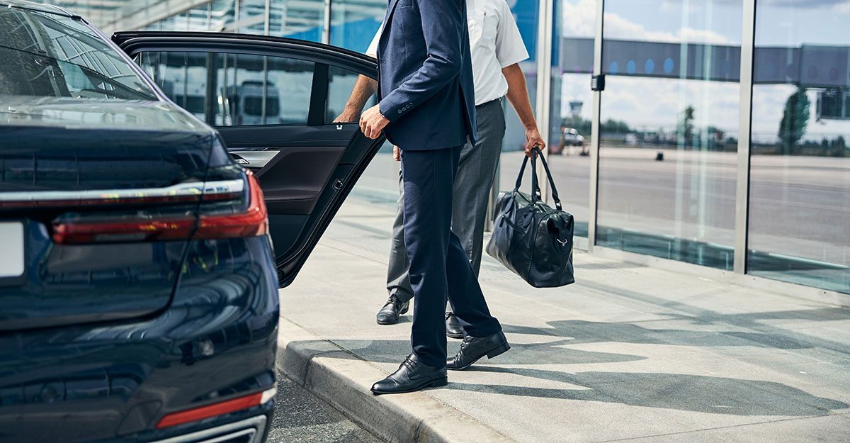 Chauffeur et passager qui sortent de la voiture à côté d'un aéroport