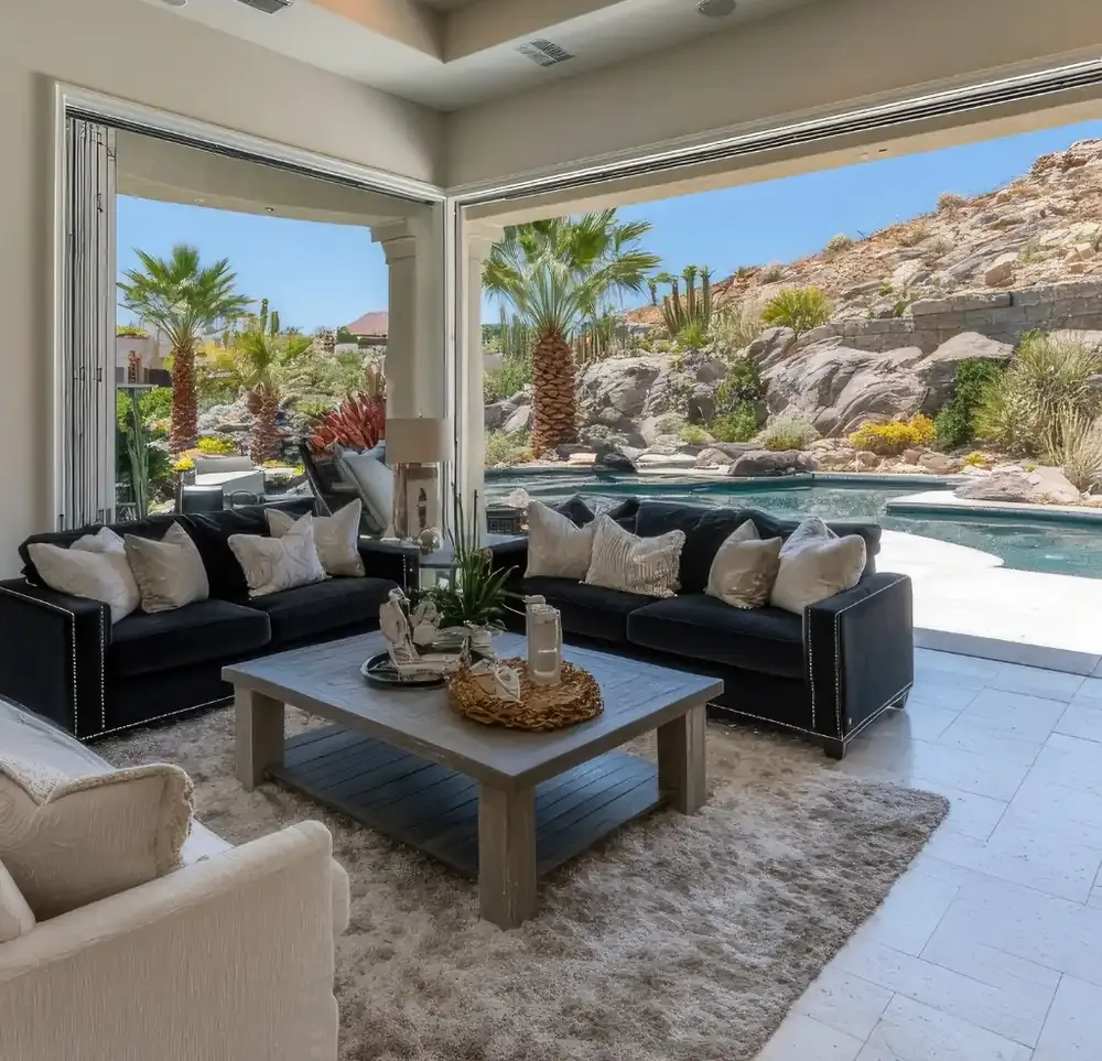 Sala de estar con sofás, mesa de café y vista abierta a la piscina y al paisaje desértico.