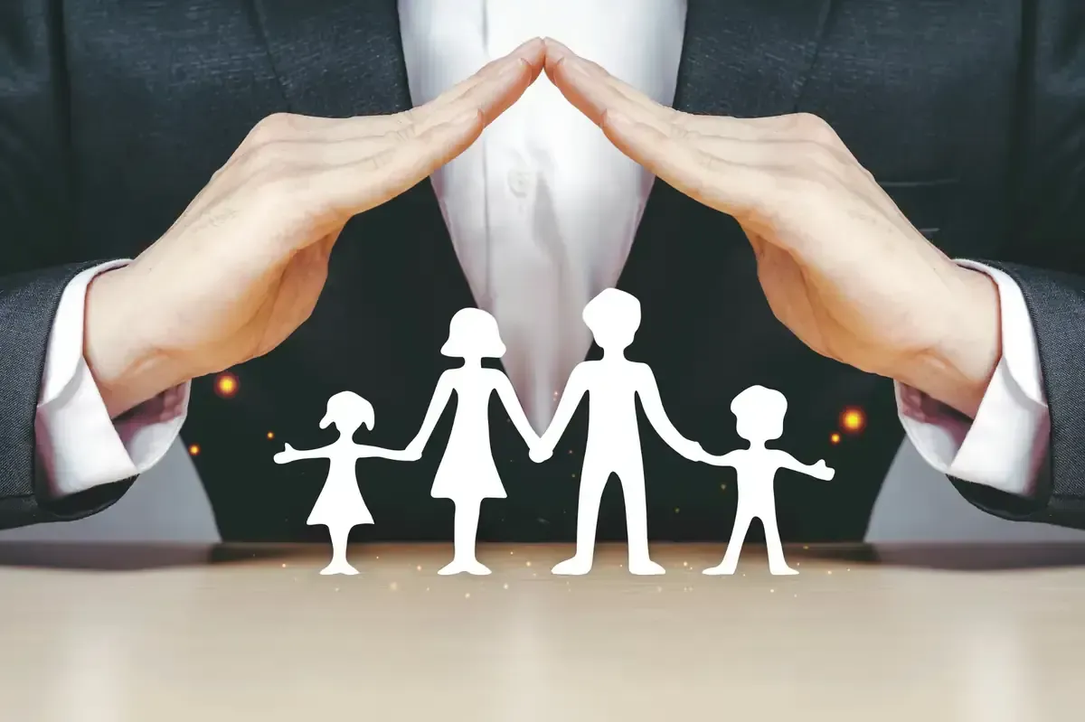 Manos que forman un techo protector sobre una familia recortada, simbolizando seguro o cuidado.
