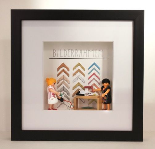 Eine Person in blauem Hemd und Jeans streicht eine dunkle Fläche mit einer Farbrolle.