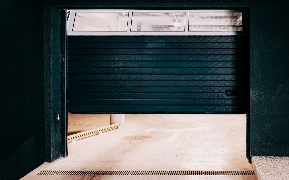 Una puerta de garaje azul está abierta en una habitación oscura.