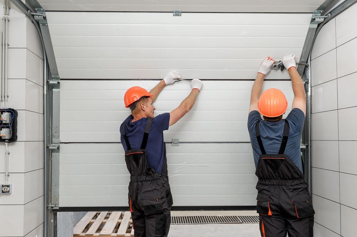 Dos hombres están instalando una puerta de garaje en un garaje.