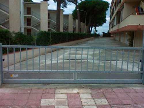 Una puerta corrediza bloquea un estacionamiento frente a un edificio.