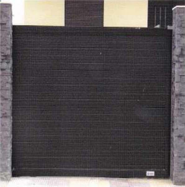 Una puerta corrediza negra está rodeada de pilares de piedra.