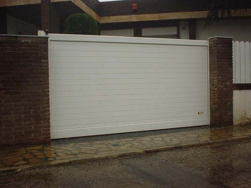 Una puerta de garaje blanca está abierta frente a un edificio de ladrillo.