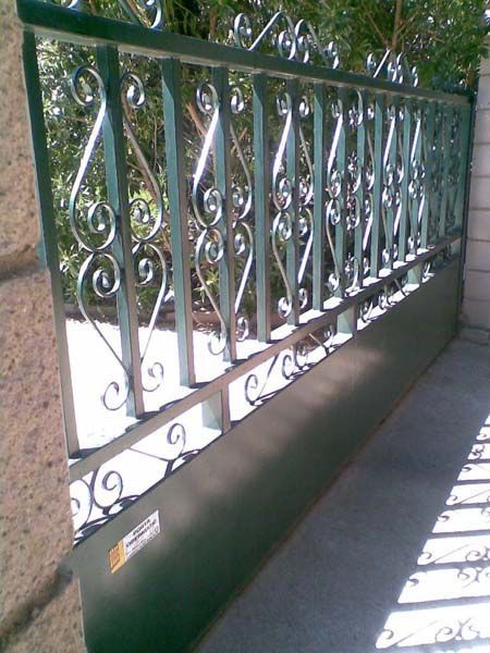 Una valla verde con un diseño de hierro forjado.