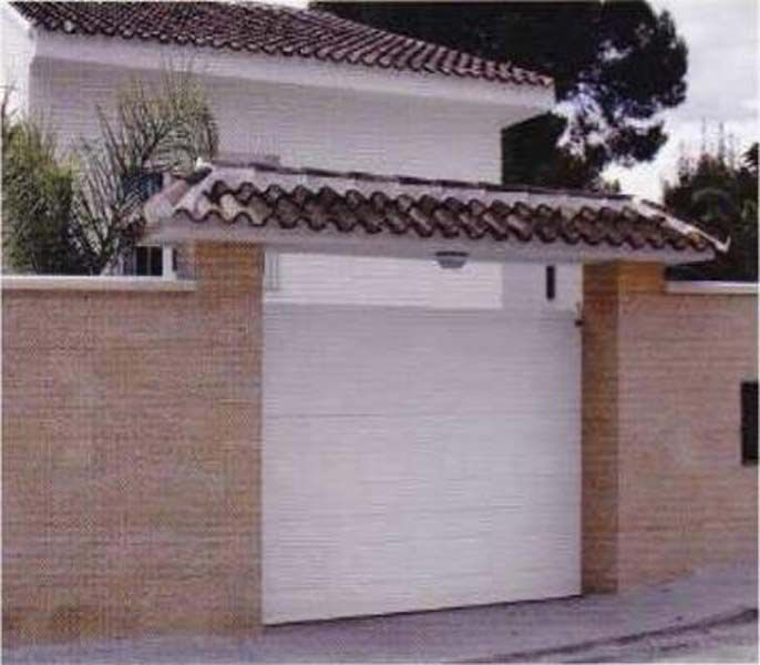 Una casa blanca con una pared de ladrillo y una puerta de garaje blanca