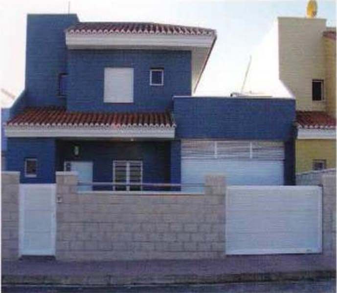 Una casa azul con una valla blanca alrededor