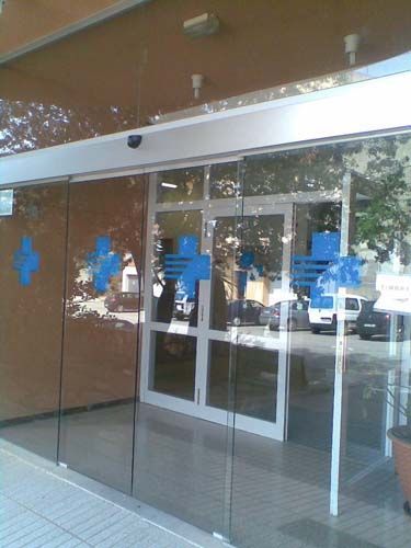 Una puerta de cristal con una cruz azul.