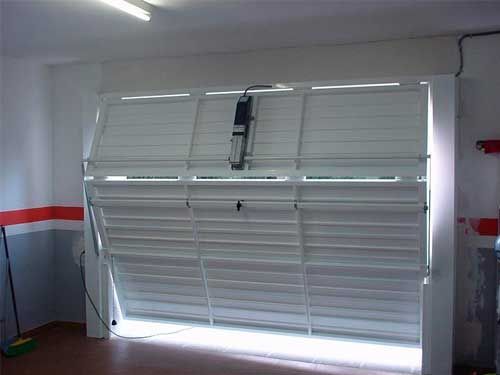 Una puerta de garaje blanca está abierta en un garaje.