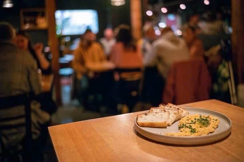 Zwei rosafarbene Cocktails mit Eis auf einer Bar in einer schwach beleuchteten Bar, im Hintergrund eine rote Lampe.