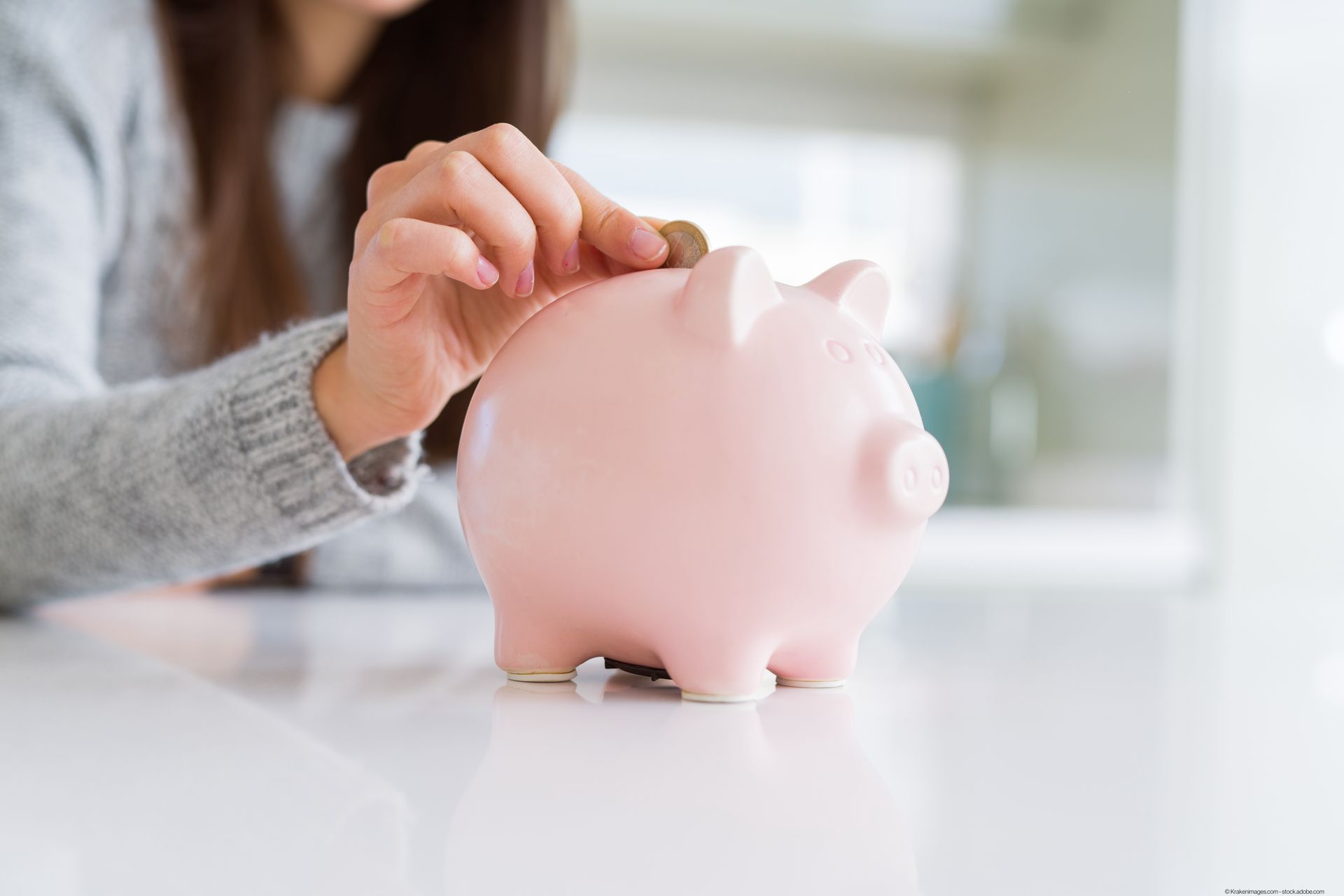 eine Frau steckt Geld in ein Sparschwein