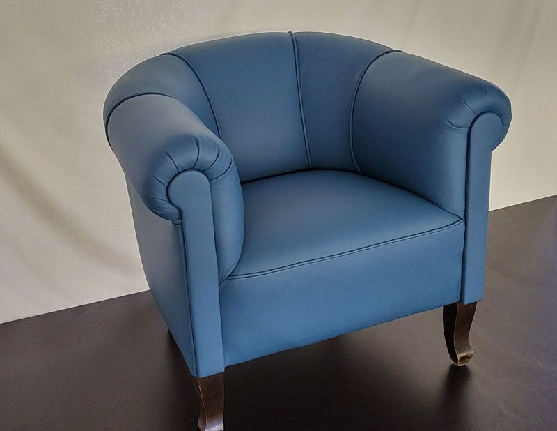 Ein blauer Ledersessel steht auf einem Holzboden