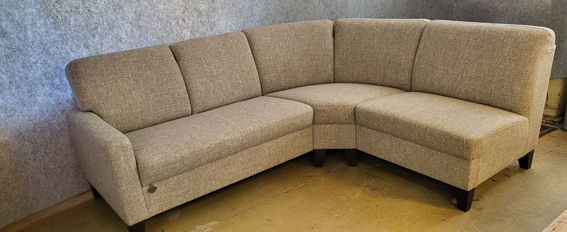 Ein beiges Sofa steht auf einem Holzboden in einem Wohnzimmer.