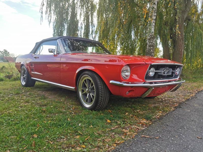 Ein rotes Ford Mustang Cabrio steht am Straßenrand.