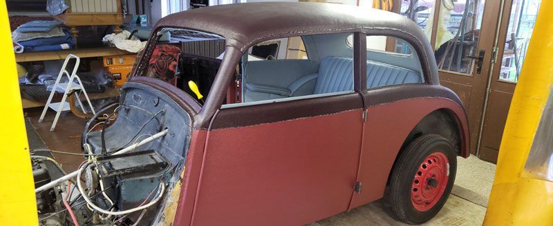 Ein altes rotes Auto steht in einer Garage.