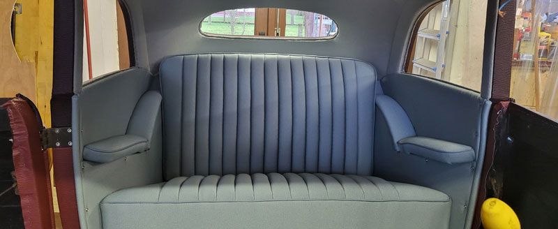 Der Rücksitz eines Autos mit blauer Sitzfläche und Armlehnen.