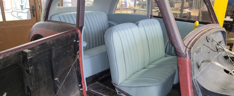 Der Innenraum eines alten Autos mit blauen Sitzen wird restauriert.