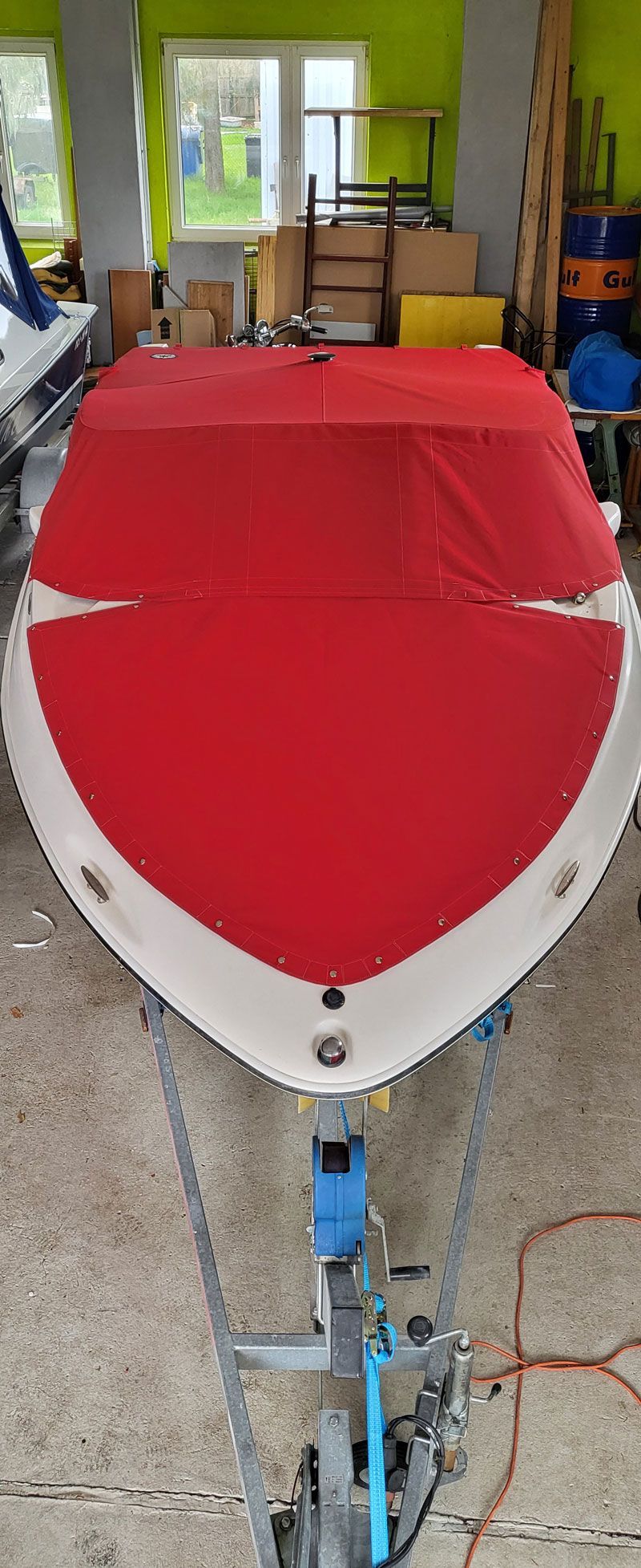 Ein rot-weißes Boot steht auf einem Anhänger in einer Garage.