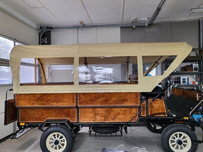 In einer Garage steht ein Holzwagen mit Überdachung.